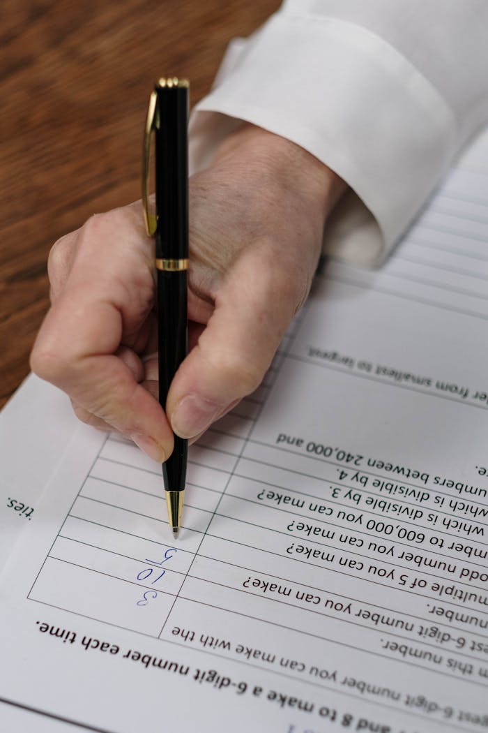 Detailed shot of a hand writing on papers with a black fountain pen, emphasizing focus and precision.